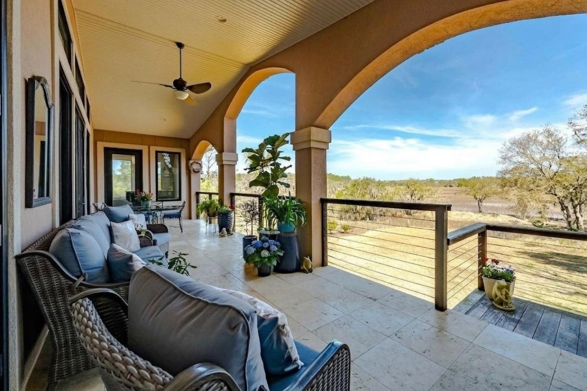 Covered upper porch with arched columns, outdoor seating, and open marsh views at 6411 China Back Lane, Meggett SC — Archfield Plantation waterfront estate