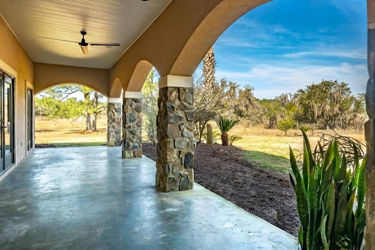 Covered arched patio with stone columns at 6411 China Back Lane, Meggett SC — ground-level suite entrance, Archfield Plantation