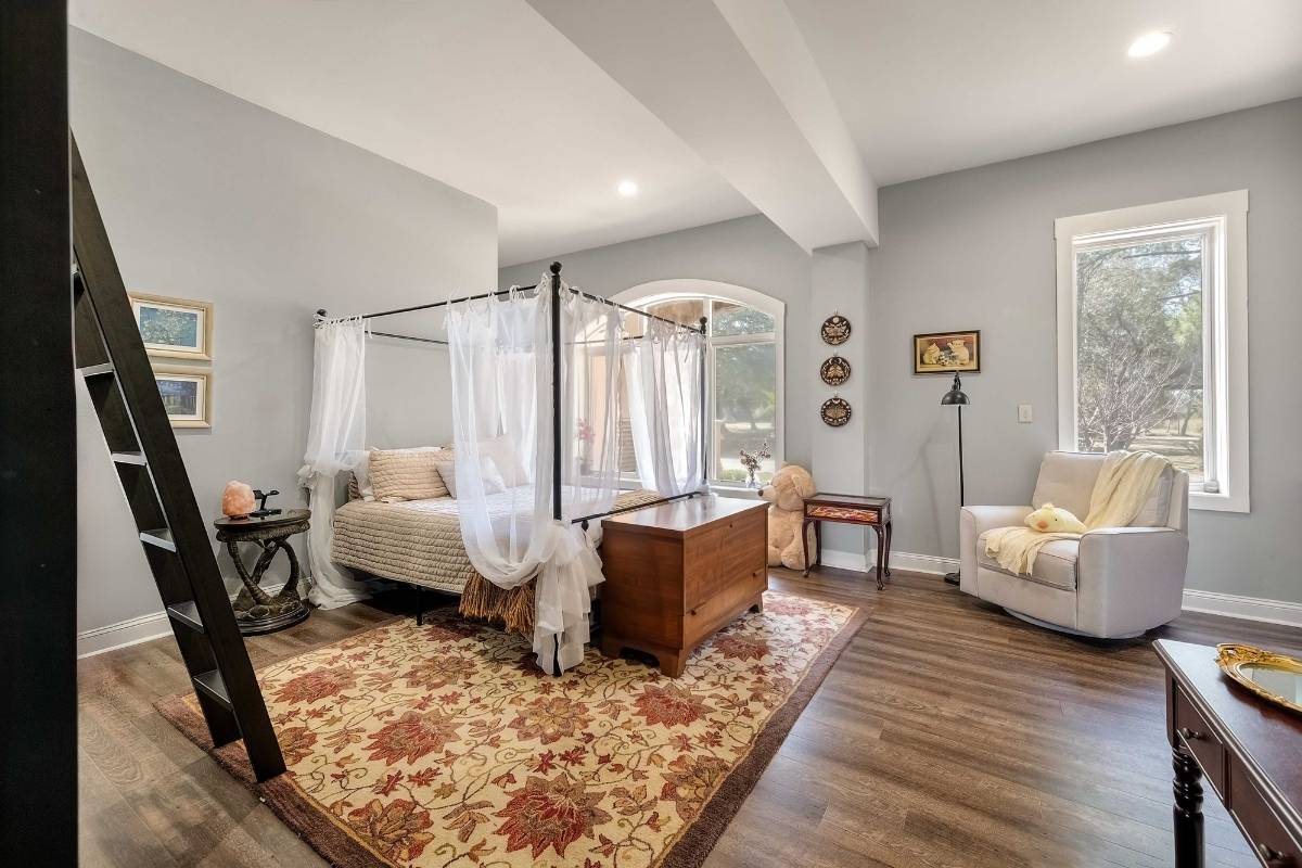 Ground-level suite bedroom with arched windows and hardwood floors at 6411 China Back Lane, Meggett SC — Archfield Plantation