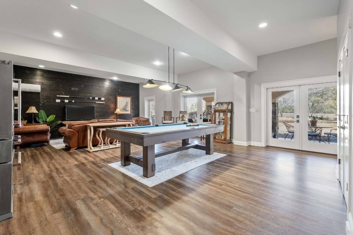 Ground-level suite great room with pool table, shiplap accent wall, and French doors to covered patio at 6411 China Back Lane, Meggett SC — Archfield Plantation