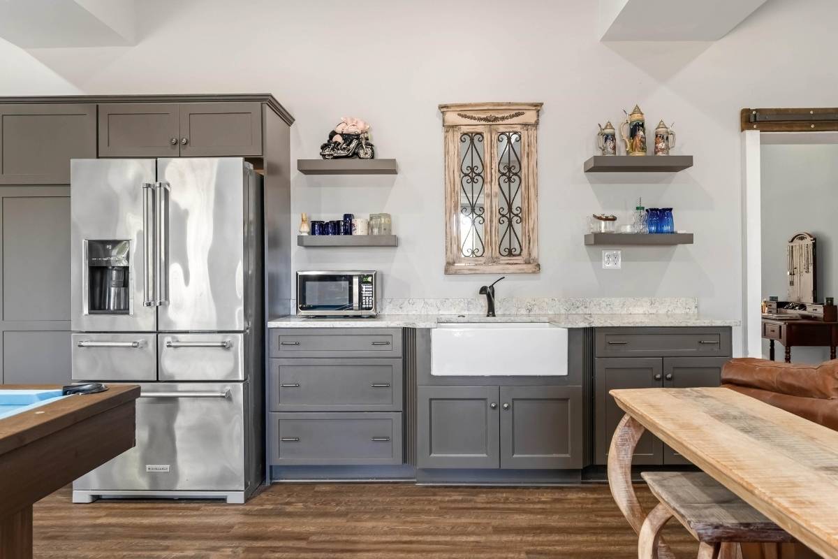 Ground-level suite kitchen with gray shaker cabinets, farmhouse sink, and stainless appliances at 6411 China Back Lane, Meggett SC