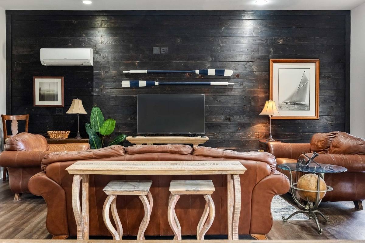 Ground-level suite living area with dark shiplap accent wall and leather seating at 6411 China Back Lane, Meggett SC