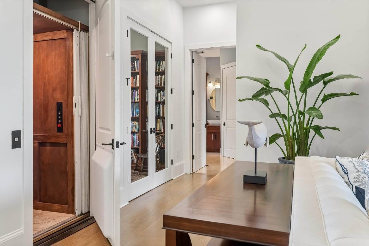 Interior hallway with elevator and French door library at 6411 China Back Lane, Meggett SC — Archfield Plantation