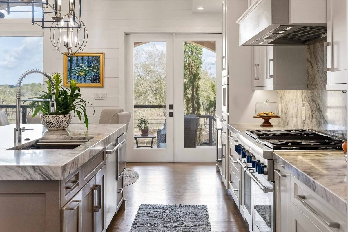 Renovated kitchen with professional gas range, marble backsplash, and French doors to covered porch at 6411 China Back Lane, Meggett SC