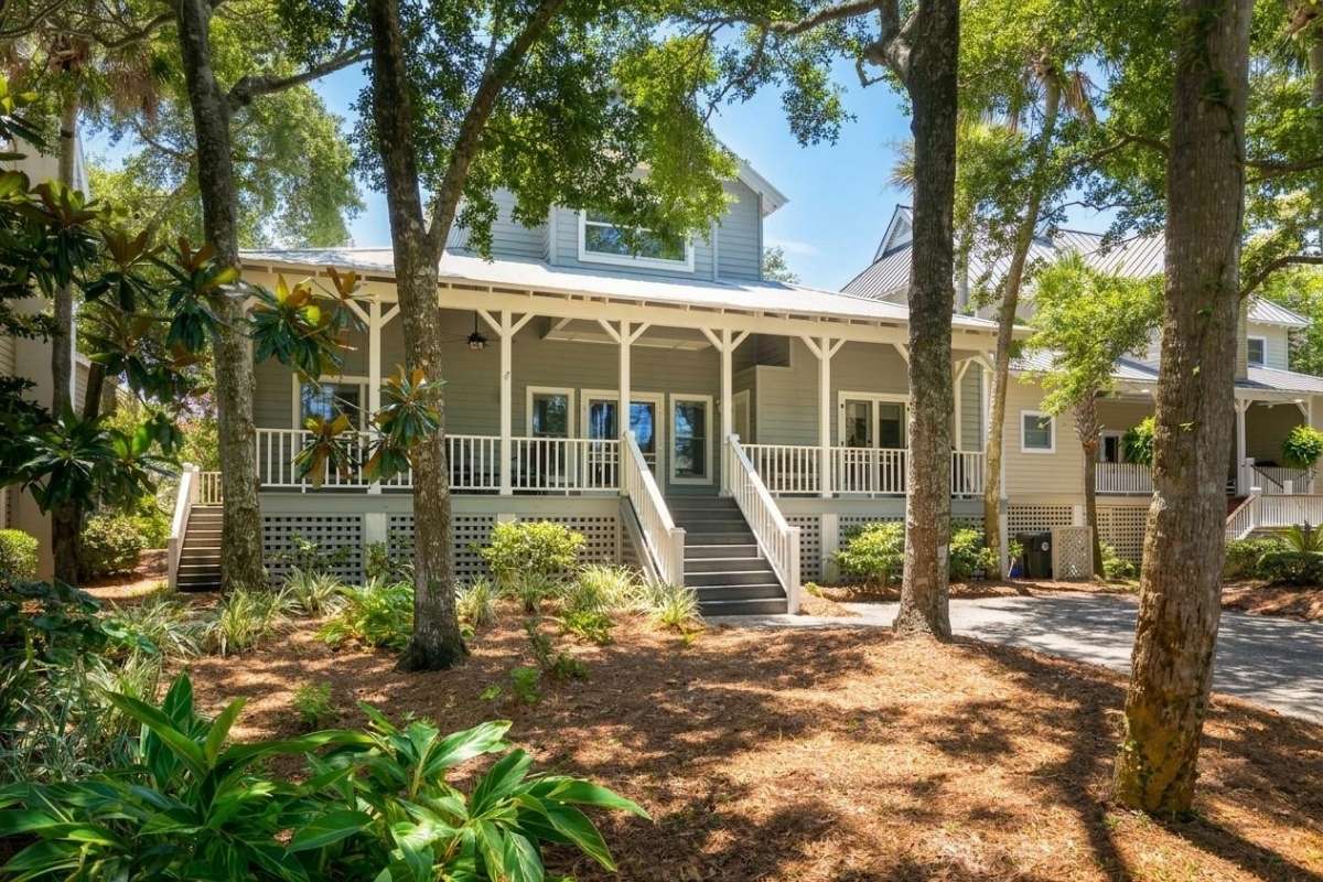 Lowcountry-style home with wide front porch, gray siding, and standing seam metal roof at Atlantic Beach, Kiawah Island