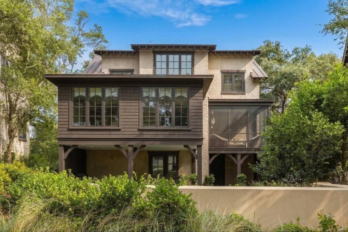Contemporary cottage exterior with dark shingle siding and screened porch at Cypress Point, Kiawah Island
