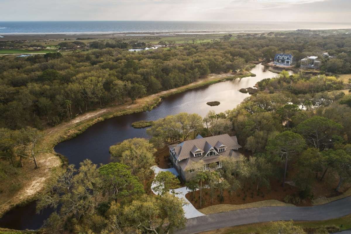 Aerial view of a custom Ocean Park home surrounded by lagoons and maritime forest with the Ocean Course and Atlantic Ocean beyond, Kiawah Island