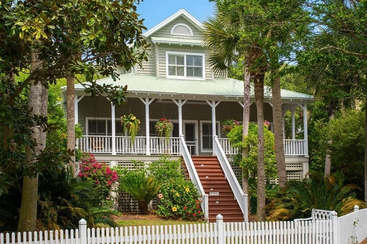 Classic beach cottage with wraparound porch, white picket fence, and blooming flowers at Turtle Beach, Kiawah Island
