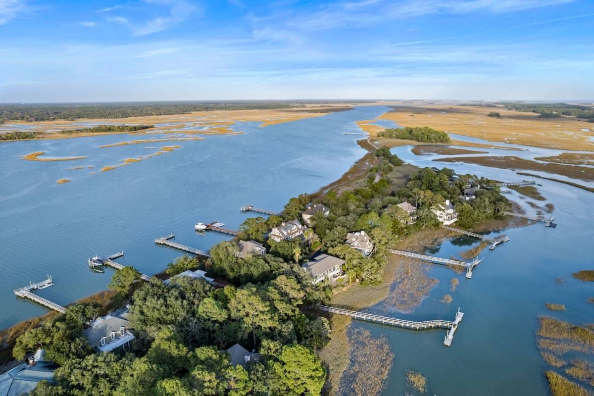 Aerial view of Rhett's Bluff homes on a wooded river peninsula with private docks and expansive marsh views, Kiawah Island SC