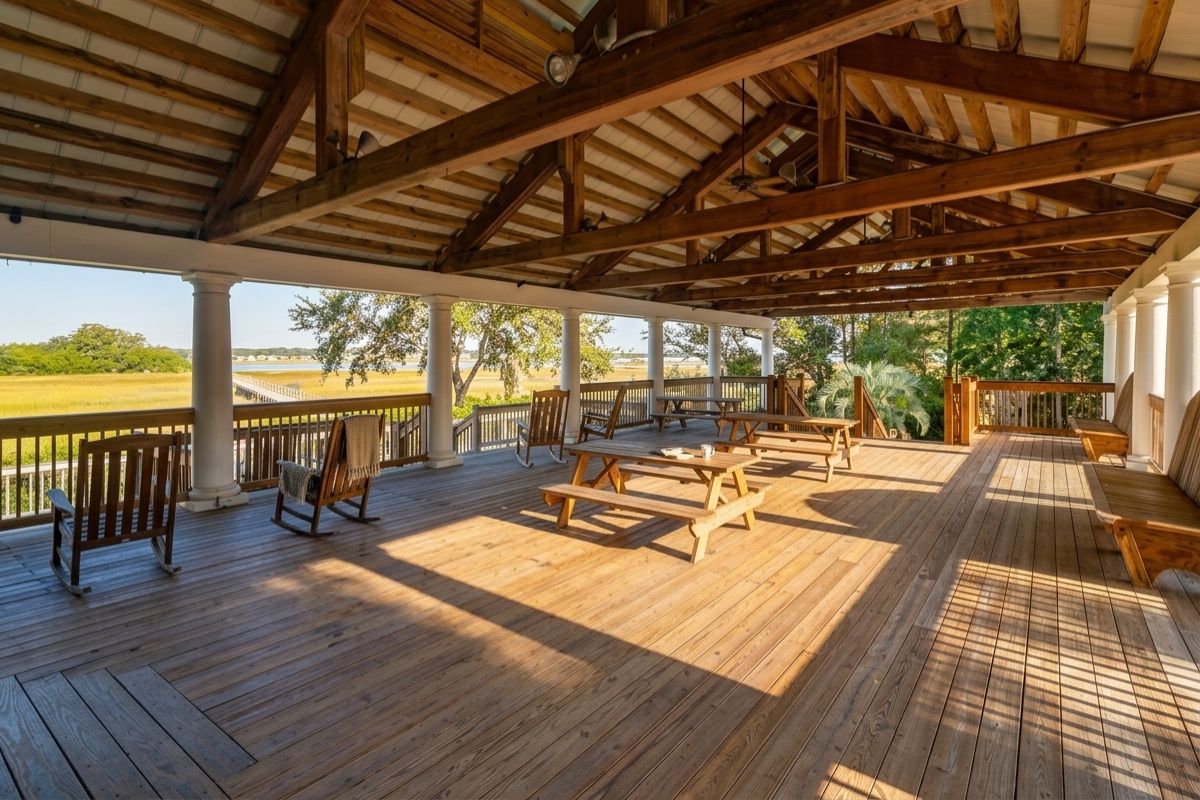 Interior of the community pavilion at Rushland Landing on Johns Island, SC, with exposed timber ceiling, rocking chairs, and views over the Stono River marsh